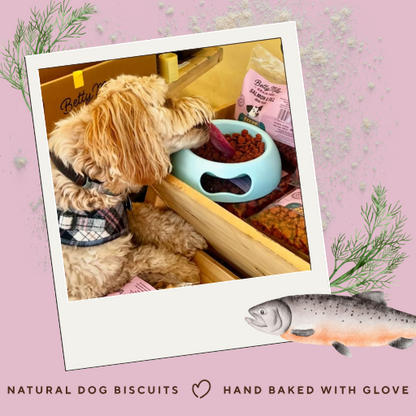 Dog eating from a bowl with a pink background and text about natural dog biscuits.